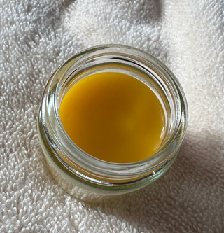 Open jar of Skin repair balm resting on a cream towel. Helps dry skin by locking in moisture to hydrate dry sensitive skin